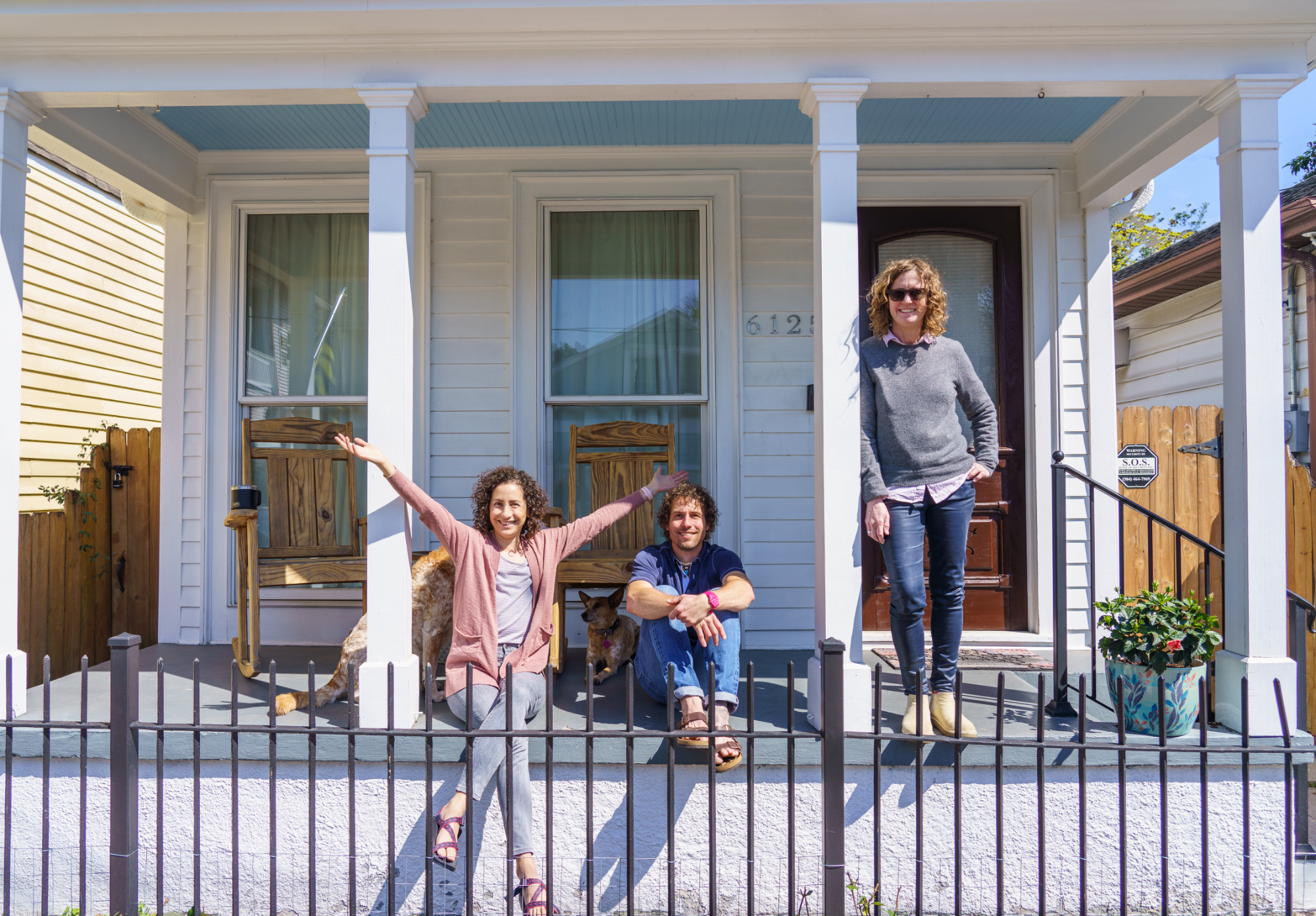 A man and woman celebrate on the front porch of their new home while Tracey Moore stands nearby