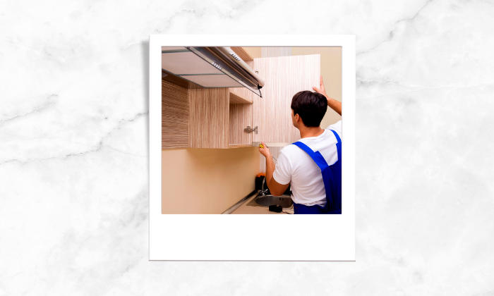 A photo of a repairman fixing a cabinet