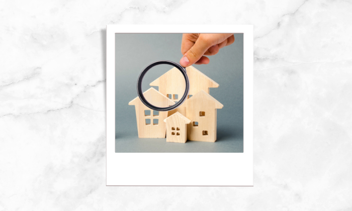 Photo of a person using a magnifying glass on some house blocks