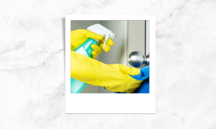 Photo of a person sanitizing and cleaning a door knob