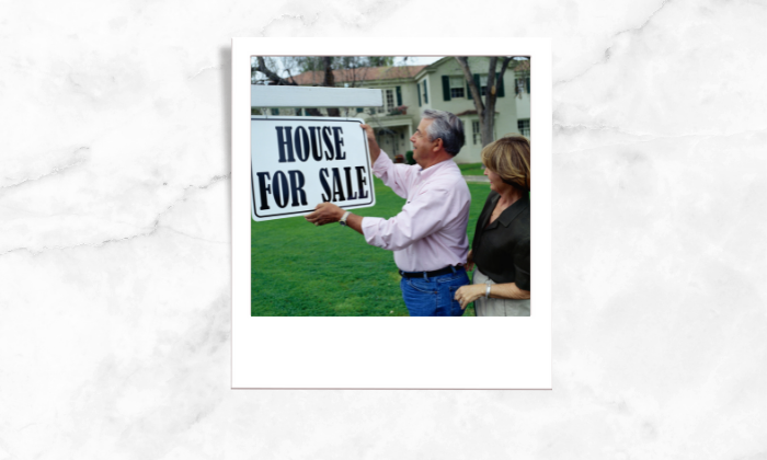 Photo of a couple putting a for sale signage