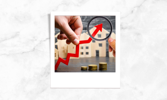 Photo of a person using magnifying glass on an illustration of a house pricing increase