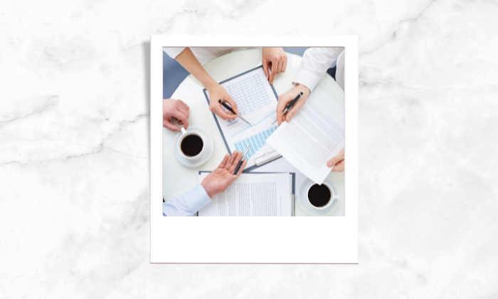 Photo of three person discussing over papers