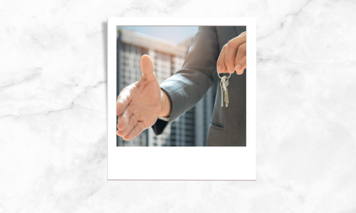 Photo of a person holding a key initiating a handshake