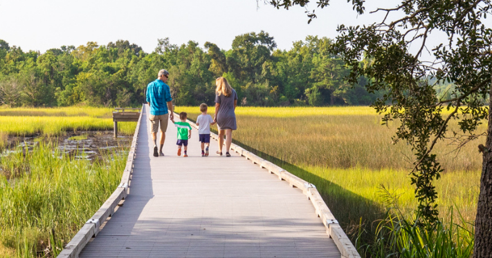 family of four walking on the boardwalk at stono river county park