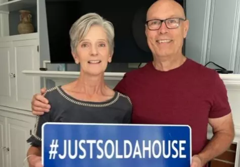 Couple holding "JUSTSOLDAHOUSE" rider