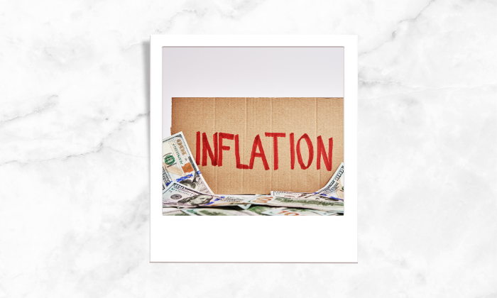 Photo of a signage with a written inflation surrounded by paper bills