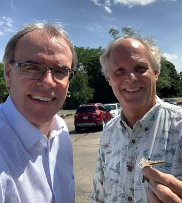 Happy Client smiling and holding a house key next to David Campbell.