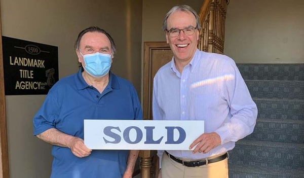 Happy client and David Campbell, Realtor holding "SOLD" sign