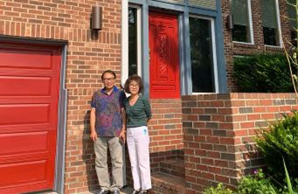 Happy Couple standing and smiling in front of house.