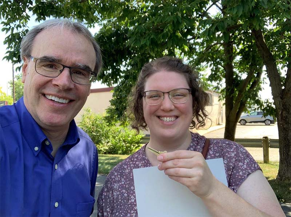 Happy client smiling and holding a key in hand next to David Campbell.