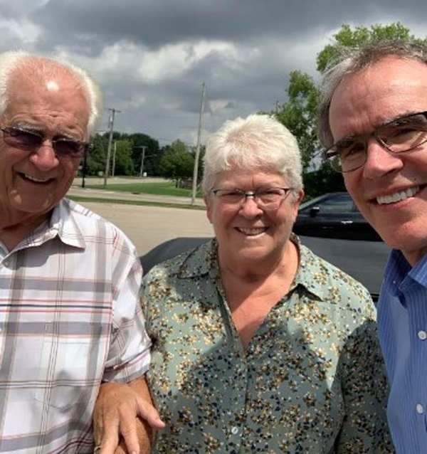 Happy couple locking arms and smiling next to David Campbell.