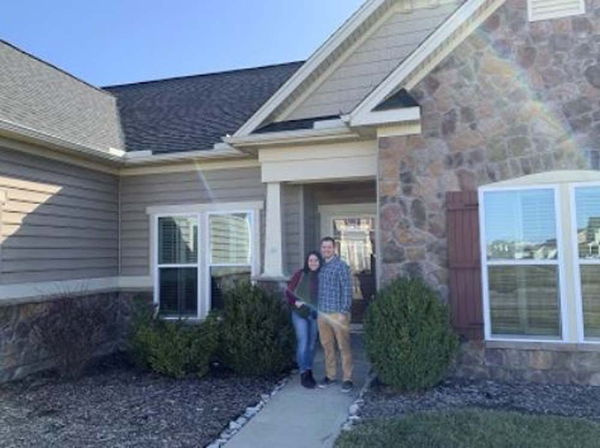 Happy couple standing in front of a house.