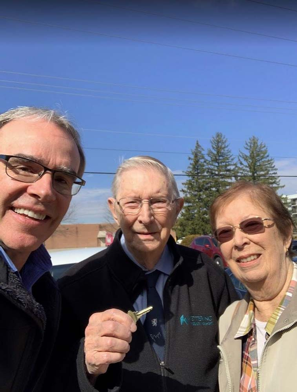 Happy couple holding house key next to David Campbell.