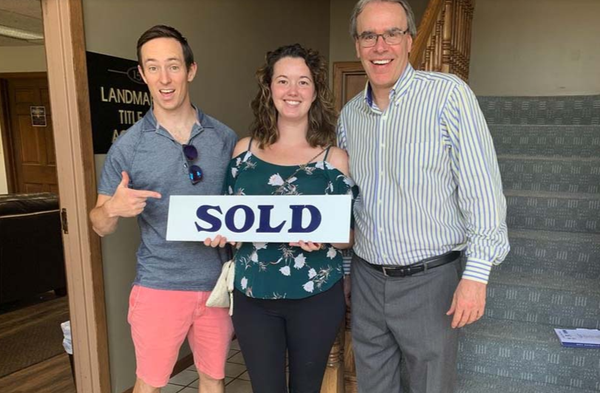 Happy clients holding a SOLD sign next to David Campbell.