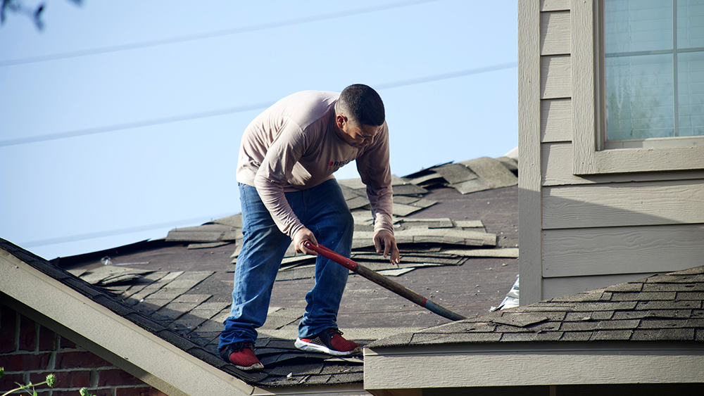 worker perfroming roof repair on a home