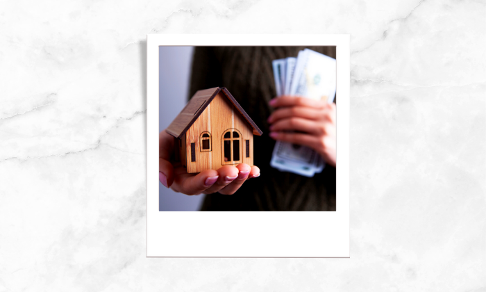 A woman holding a toy house and money