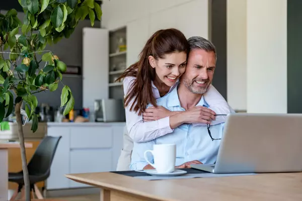 happy-couple-at-table-at-home-sharing-a-laptop-2022-12-16-22-29-00-utc (1)