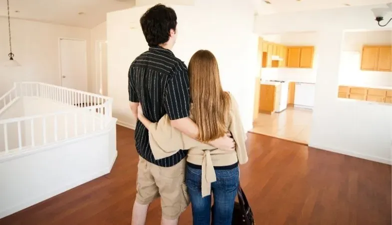 young couple standing in new empty home imagining what to do with the place