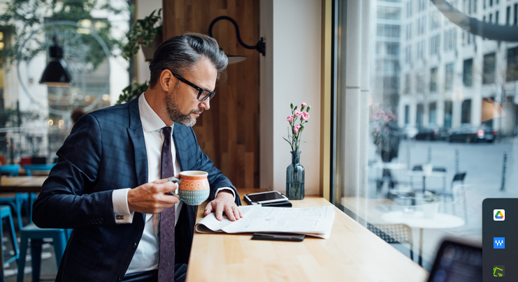Investor at coffee shop drinking from mug and reading newspaper