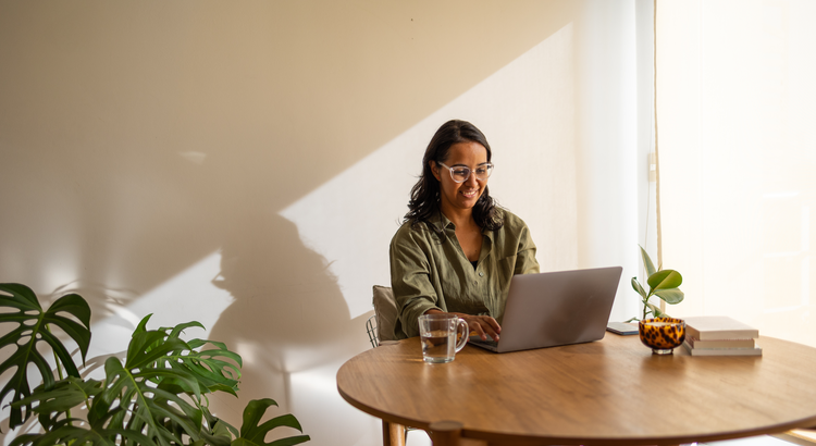 Person looking at laptop while sitting down with coffee cup