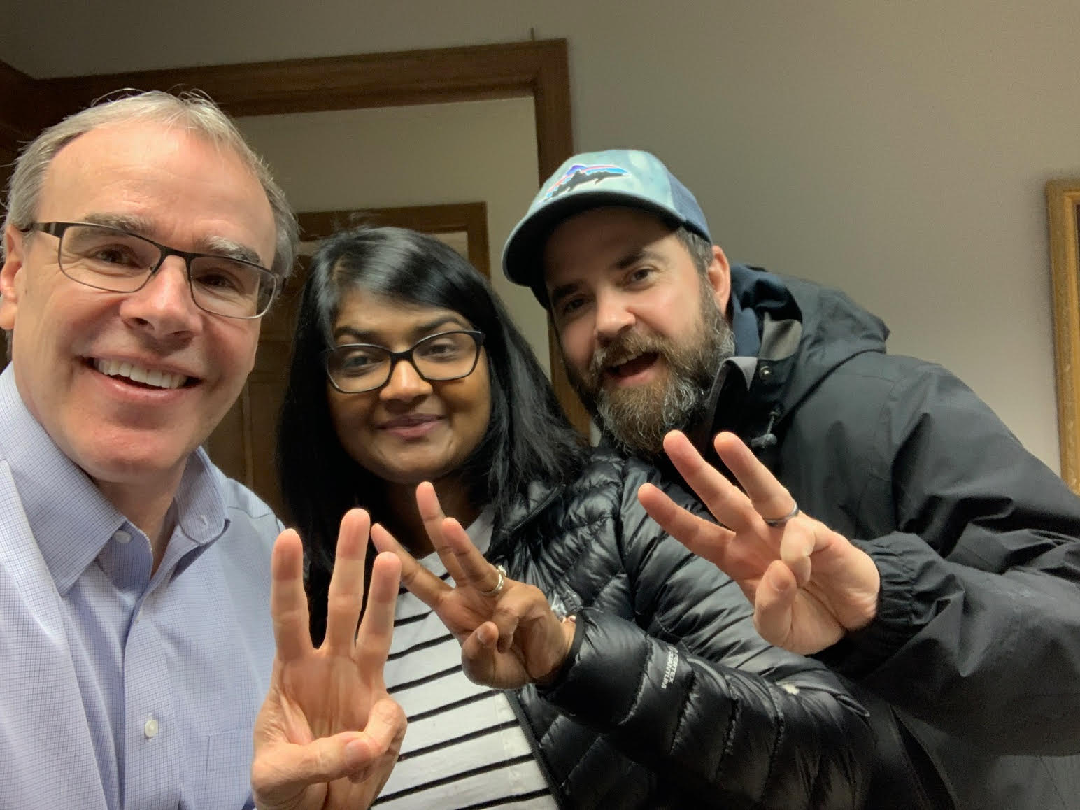 Two happy clients - a man and woman - stand next to David Campbell, Realtor. All three are smiling towards the camera, holding up three fingers.