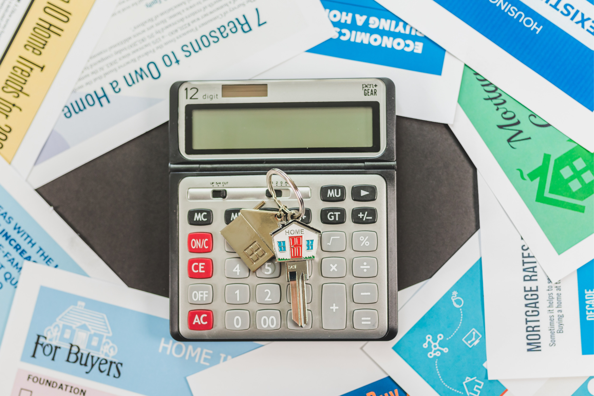 Calculator with house keys and a stack of papers about buying a house