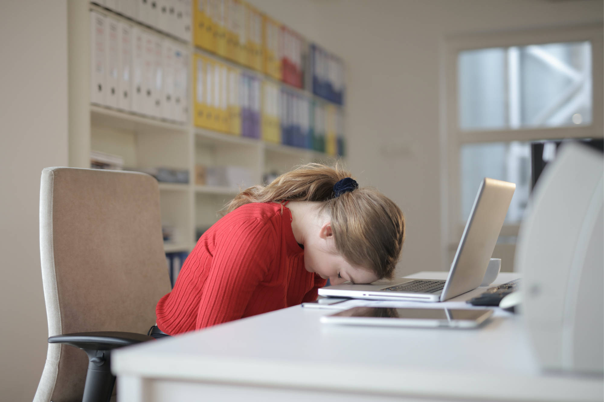 Woman sitting a table with laptop, her head is on the table expressing disappointment