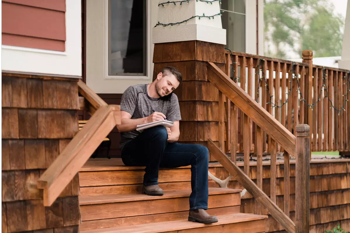 cochrane alberta real estate agent sitting on wooden front porch, taking notes while on the phone