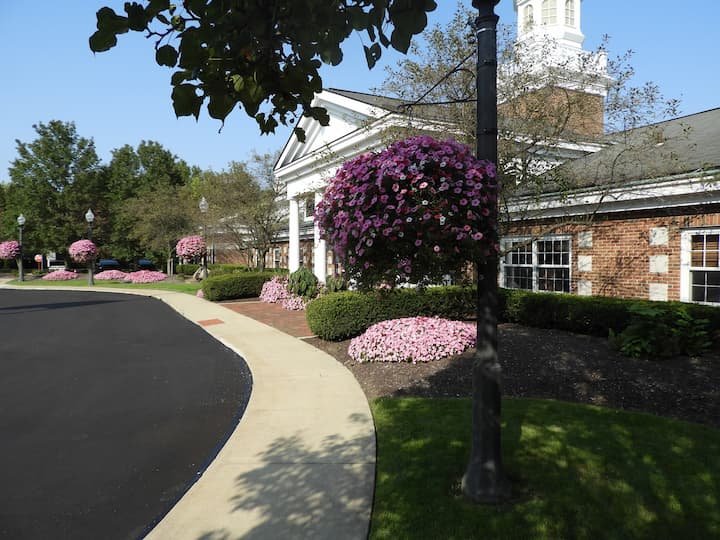 Side street view of Orange Village Ohio City Hall, a colonial brick building with white trims and landscaping featuring blossoming spring flowers located near homes for sale in Orange Village Ohio