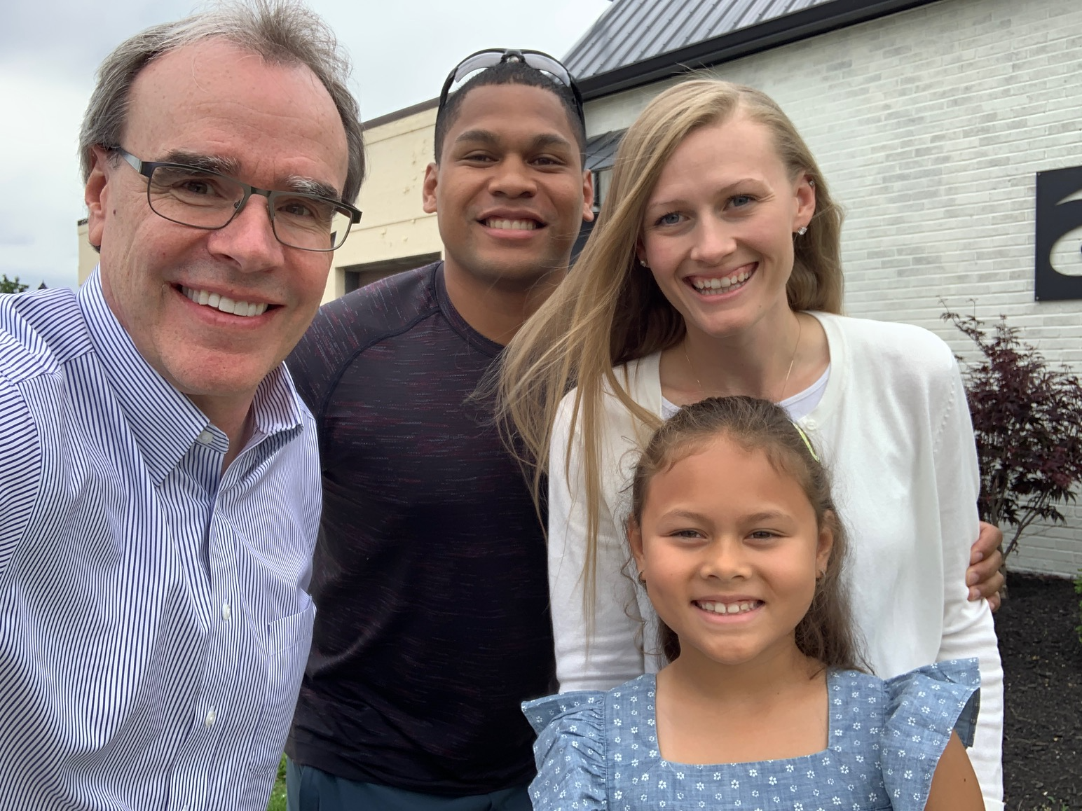 Two happy clients - a man and woman - stand with their daughter next to David Campbell, Realtor. They're all facing the camera, smiling.