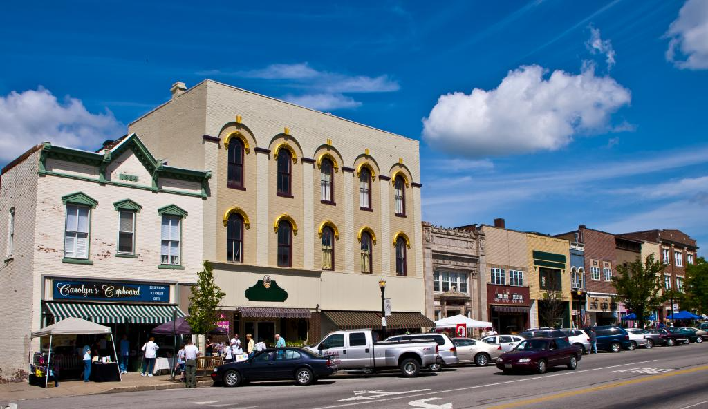 view of downtown main street with several white buildings, store at street level, car parked on the side and people walking, located near homes for sale in Wadsworth Ohio