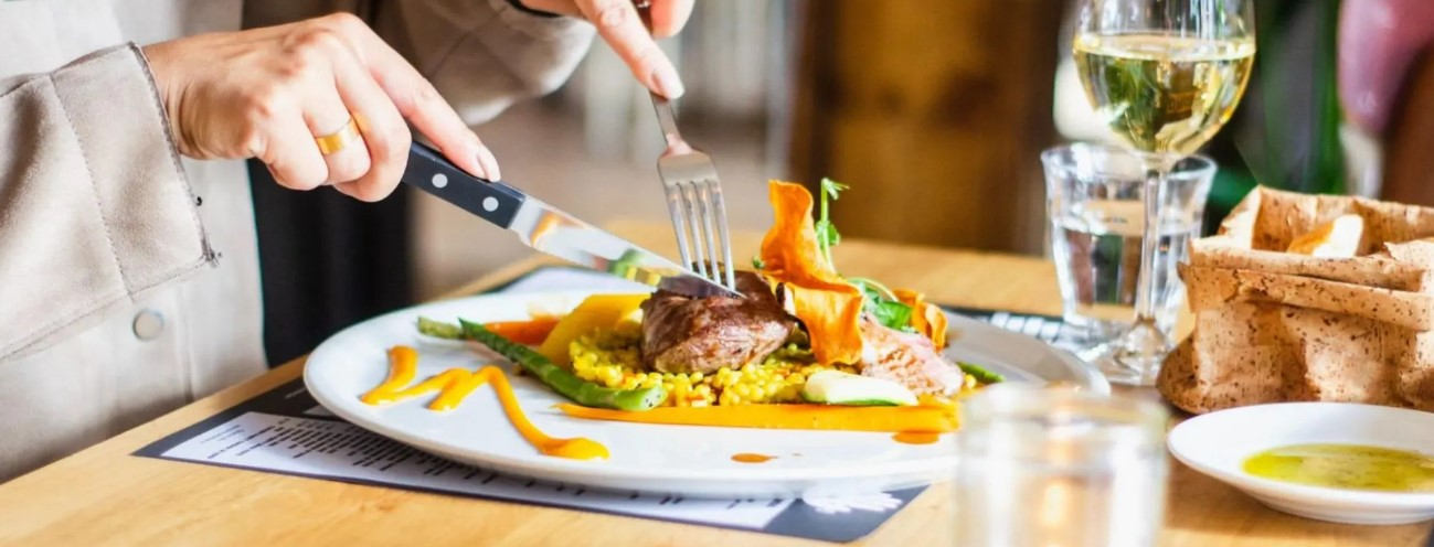 a person cutting a piece of meat while eating at one of Naomi's favorite restaurants in Austin