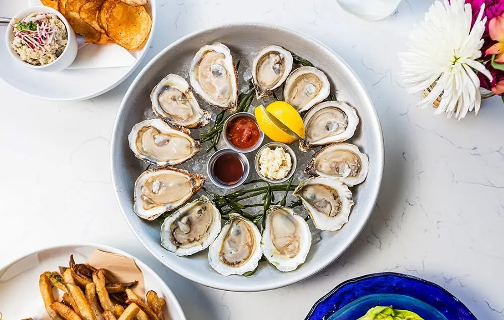 a platter of oysters on a table with other plates of food