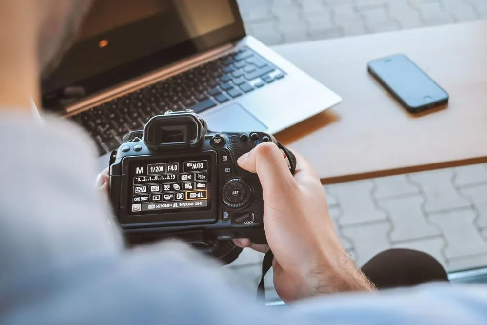 hands holding a camera showing the back screen