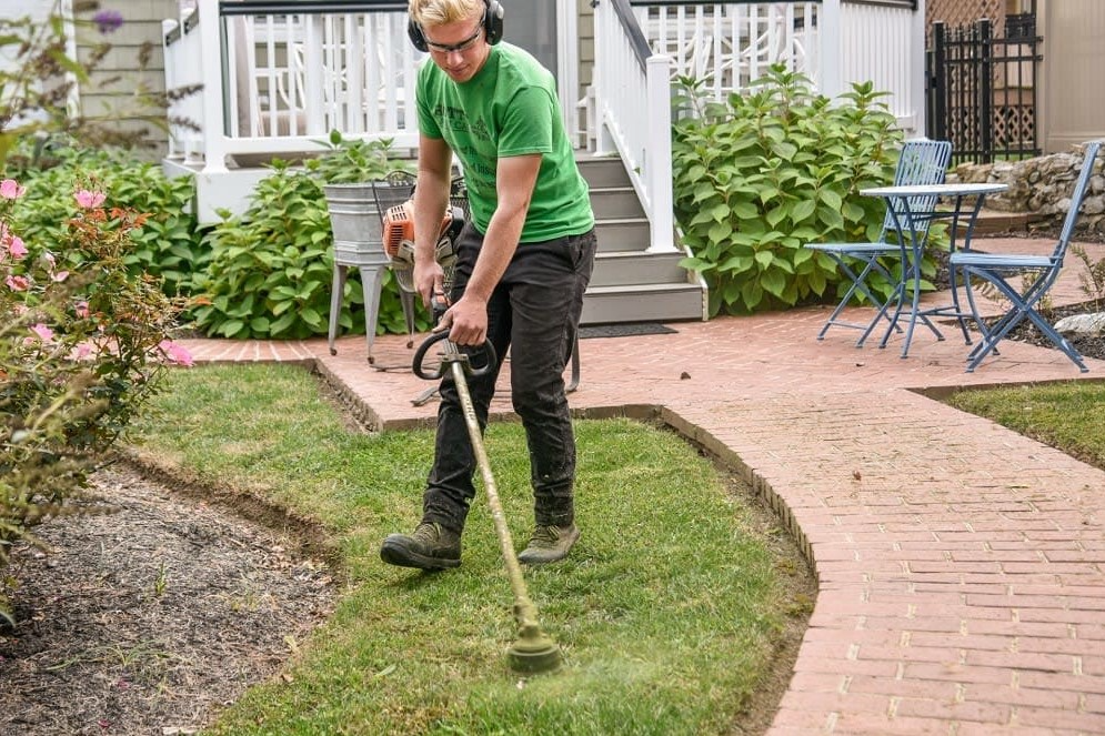 landscaper weed eating a yard to improve curb appeal