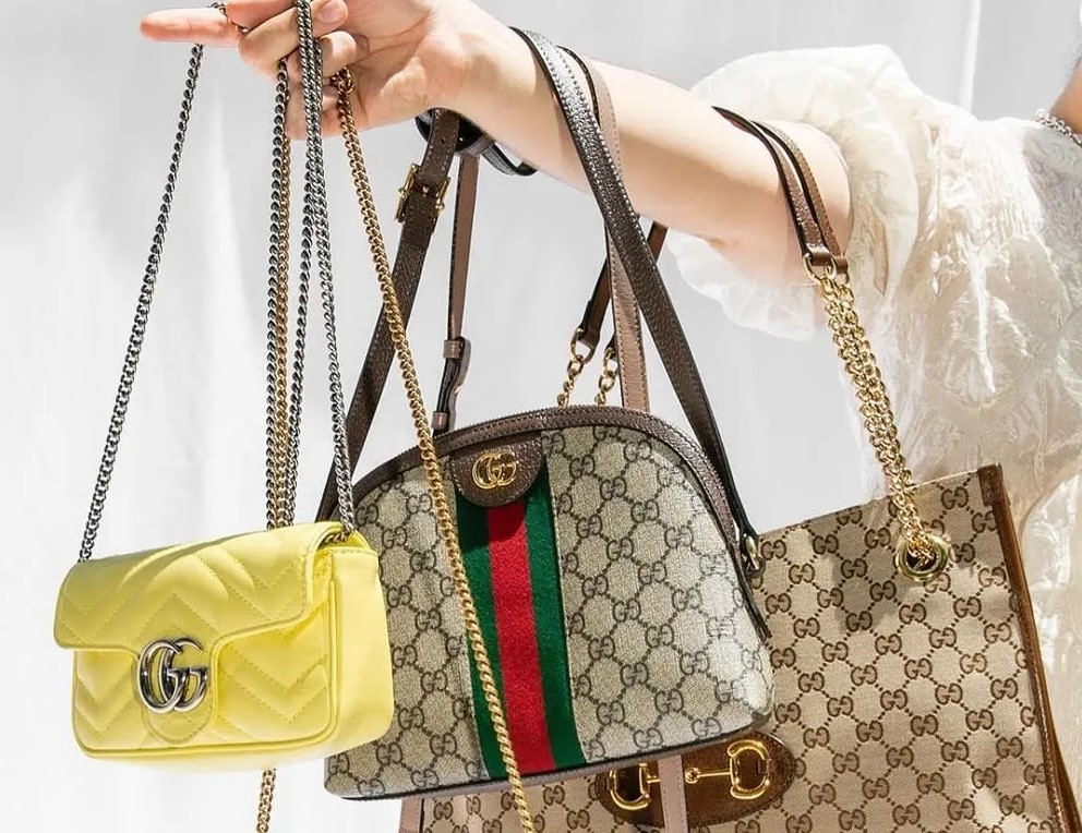 a woman holding three gucci bags on her arm