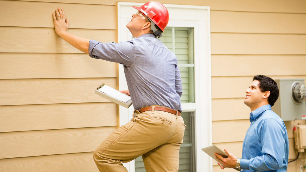 "Professional home inspector examining a residential property in Miami with a clipboard, pointing out important features to potential buyers."
