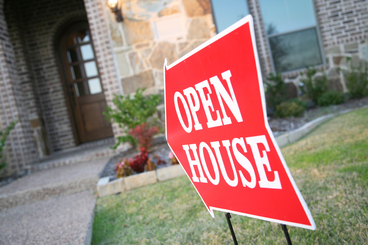 Red and white open house sign in front of a single-family home