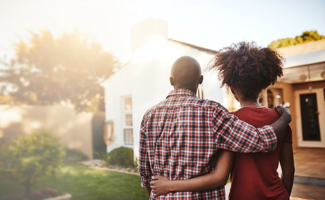 First-time home buyers standing next to one another admiring their new home