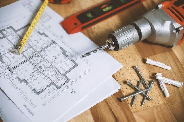 Drill with screws on top of blueprints of a house