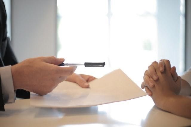 A person handing over a contract.