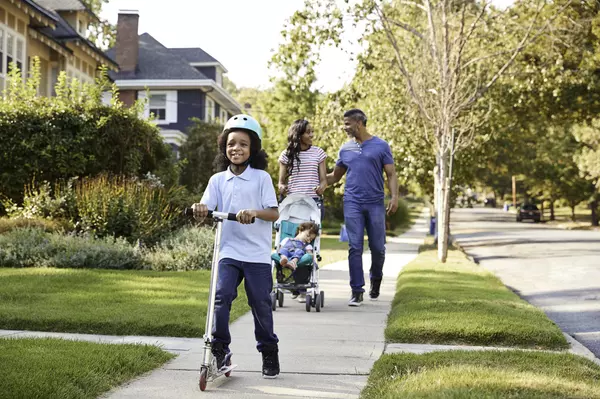 couple-push-daughter-in-stroller-as-son-rides-scooter