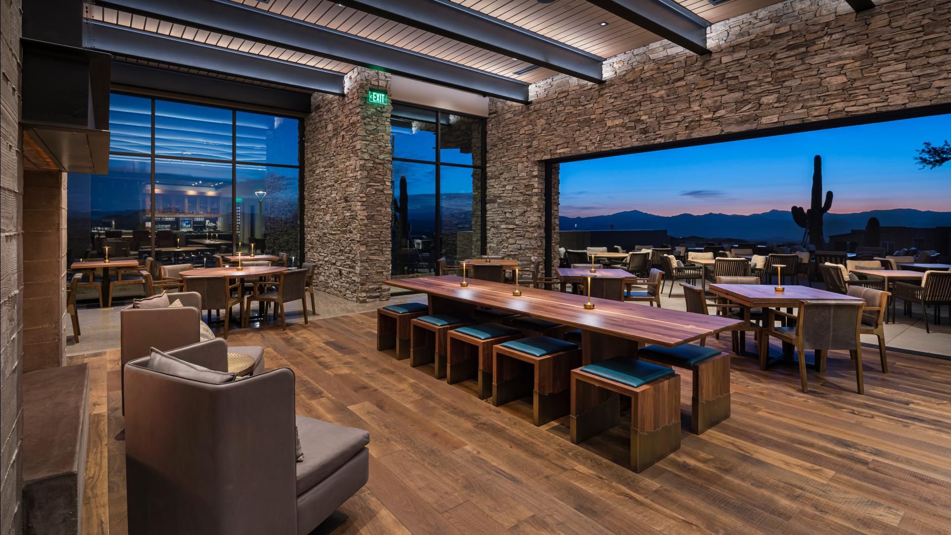 Luxury dining area with floor-to-ceiling windows and stunning desert and mountain views at sunset – highlights the importance of community insights when choosing a new home, including access to top-rated amenities, scenic surroundings, and vibrant lifestyle offerings that align with long-term investment goals.