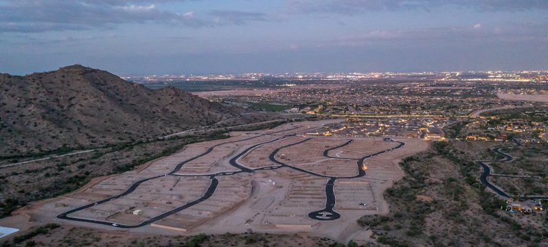 Aerial view of a new community development with mountain backdrop – highlights how working with The Ravenscroft Group provides exclusive access to the first lots available in new communities, along with benefits like special pricing incentives, early updates, and expert negotiation to secure the best deal.