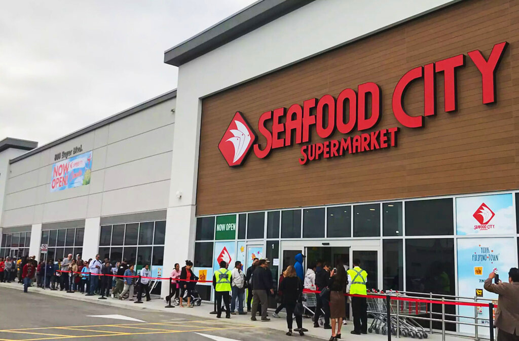 Seafood City Supermarket grand opening at Chandler Fashion Center, drawing in large crowds eager to explore the new Filipino-American grocery store. The image showcases the exterior of the store, highlighting its prominent signage and a bustling line of excited customers ready to experience its unique offerings in Chandler, AZ.