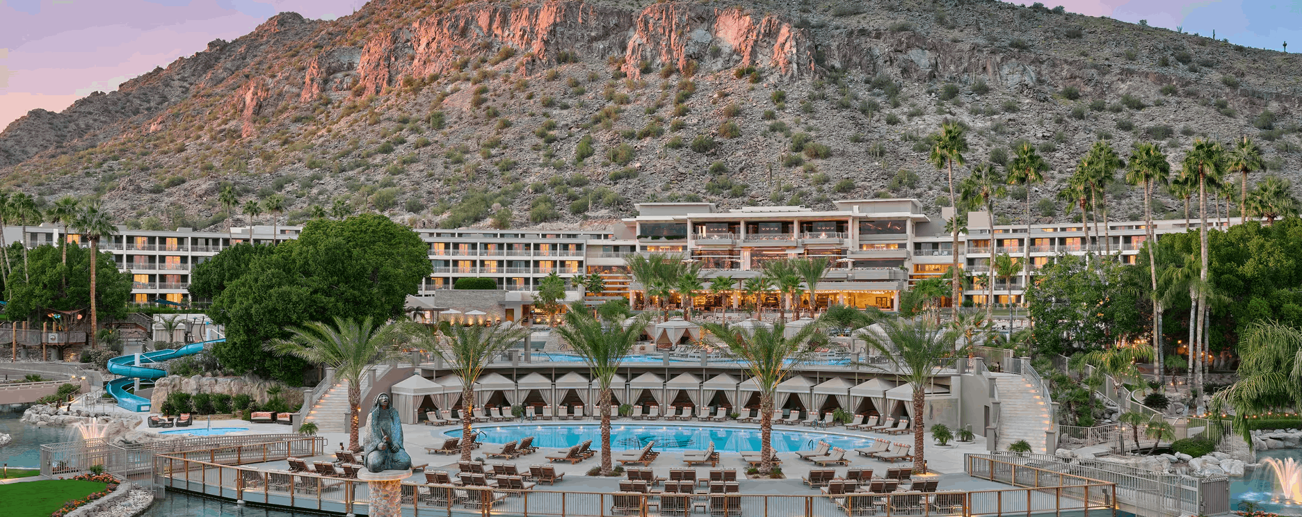 The luxurious Phoenician resort in Scottsdale, Arizona, nestled at the base of Camelback Mountain, featuring its stunning pool area, palm trees, and elegant cabanas with the iconic desert landscape in the background.