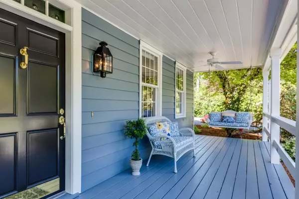 front porch of a blue house with a black door and porch furniture