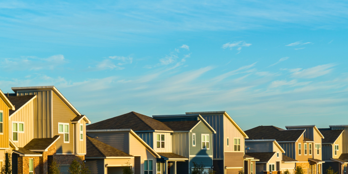 Suburban neighborhood with modern single-family homes under a clear sky, symbolizing the steady growth of the housing market. Highlights long-term drivers in real estate, such as population growth, economic stability, and demand for residential spaces, which influence housing trends more consistently than short-term events.