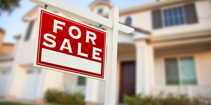 Red 'For Sale' sign in front of a suburban home, symbolizing opportunities in the housing market. Highlights the benefits for buyers and sellers who take action rather than waiting, as market conditions and interest rates can shift, making it advantageous to move forward in real estate decisions.